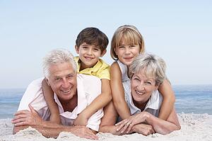 Grandparents And Grandchildren Relaxing On Beach Holiday