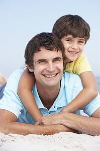 Father And Son Relaxing On Beach Holiday
