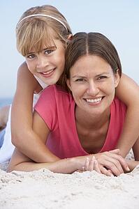 Mother And Daughter Relaxing On Beach Holiday