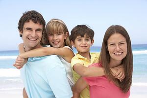 Family Having Piggyback Fun On Beach Holiday