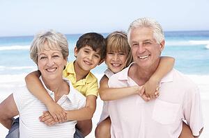 Grandparents And Grandchildren Relaxing On Beach Holiday