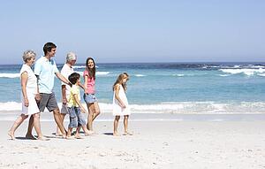 Three Generation Family Walking Along Sandy Beach