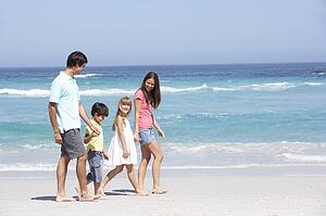 Family Walking Along Sandy Beach