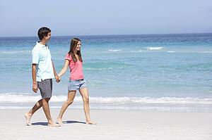 Couple On Holiday Walking Along Sandy Beach