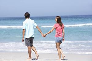 Couple On Holiday Walking Along Sandy Beach