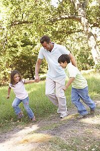 Father And Children Enjoying Walk In Park