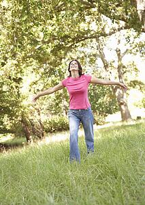 Young Woman Running Through Long Grass In Park