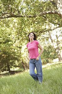 Young Woman Walking Through Long Grass In Park