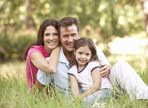 Family Sitting In Long Grass In Park
