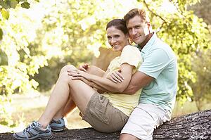 Young Couple In Walking Clothes Resting On Tree In Park