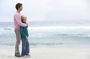 Father And Son Standing On Winter Beach Together
