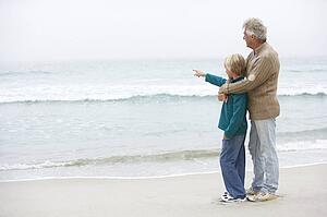Grandfather And Son Standing On Winter Beach Together