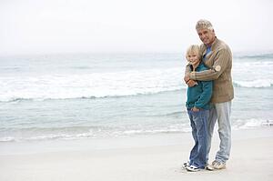 Grandfather And Son Standing On Winter Beach Together