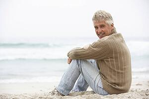 Senior Man On Holiday Sitting On Winter Beach