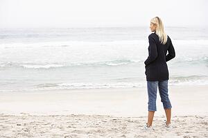 Young Woman On Holiday Standing On Winter Beach