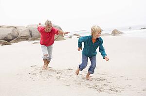 Grandfather Chasing Grandson Along Winter Beach