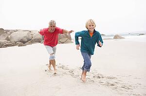 Grandfather Chasing Grandson Along Winter Beach