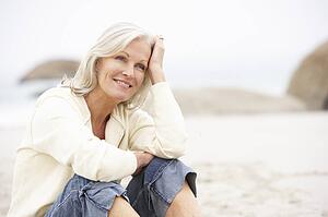 Senior Woman On Holiday Sitting On Winter Beach
