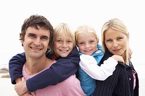 Young Family Sitting On Winter Beach