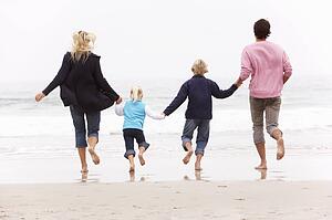 Back View Of Young Family Running Along Winter Beach