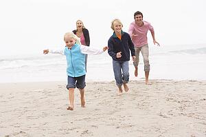 Young Family Running Along Winter Beach