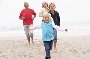 Grandparents And Grandchildren Running On Winter Beach Together