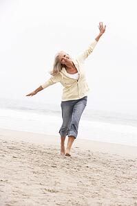 Senior Woman On Holiday Running Along Winter Beach