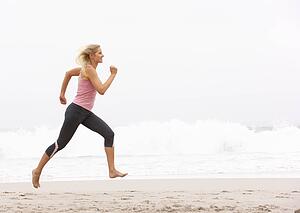Young Woman Running Along Winter Beach