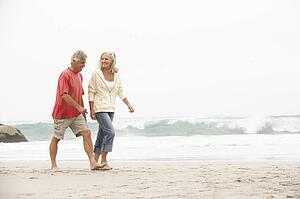 Senior Couple On Holiday Running Along Winter Beach