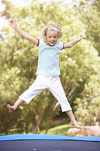 Young Girl Jumping On Trampoline In Garden