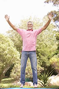 Senior Man Jumping On Trampoline In Garden