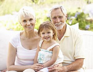 Grandparents And Granddaughter Relaxing In Garden