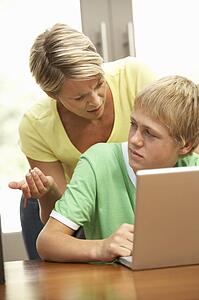 Angry Mother And Teenage Son Using Laptop At Home