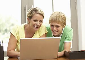 Mother And Teenage Son Using Laptop At Home