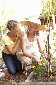 Senior Woman And Adult Daughter Relaxing In Garden