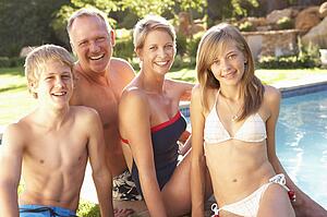 Young Family Relaxing By Pool In Garden
