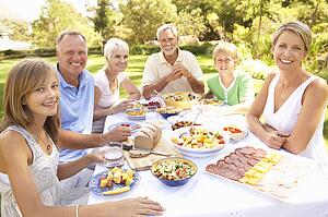 Extended Family Enjoying Meal In Garden