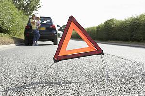 Mother And Daughter Broken Down On Country Road With Hazard Warning Sign In Foreground