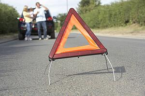 Family Broken Down On Country Road With Hazard Warning Sign In Foreground
