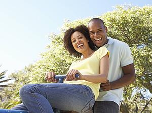 Portrait Of Young Couple Riding On SeeSaw In Park