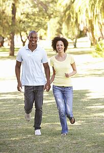 Portrait Of Young Couple Running Through Park