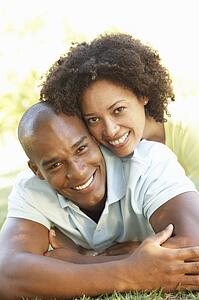 Portrait Of Young Couple Laying On Grass In Park
