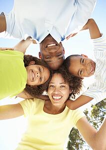 Portrait of Happy Family Looking Down Into Camera In Park