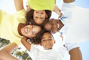 Portrait of Happy Family Looking Down Into Camera In Park
