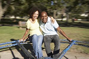 Young Couple Riding On Roundabout In Park
