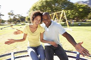 Young Couple Riding On Roundabout In Park