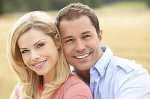 Couple Sitting On Straw Bales In Harvested Field