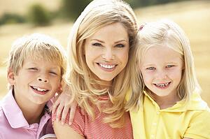 Mother And Children Sitting On Straw Bales In Harvested Field