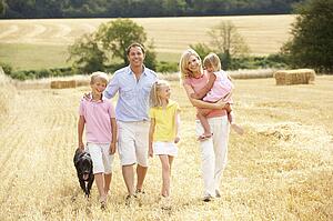 Family Walking Together Through Summer Harvested Field