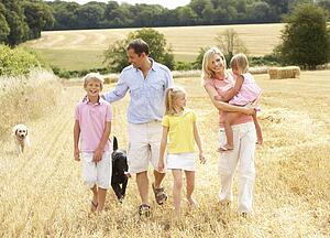 Family Walking Together Through Summer Harvested Field